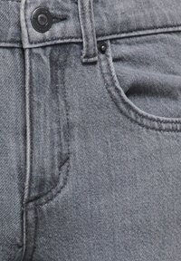 Sive kavbojne iz jeansa z zapiranjem na gumbe, dizajnom s petimi žepi in vidnimi šivi. Gladek tekstura z rahlo obrabljenim videzom.