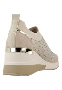 Zapatilla cuña beige con parte superior texturizada, acentos metálicos y un diseño elegante. Presenta una suela acolchada y una lengüeta para facilitar su uso.