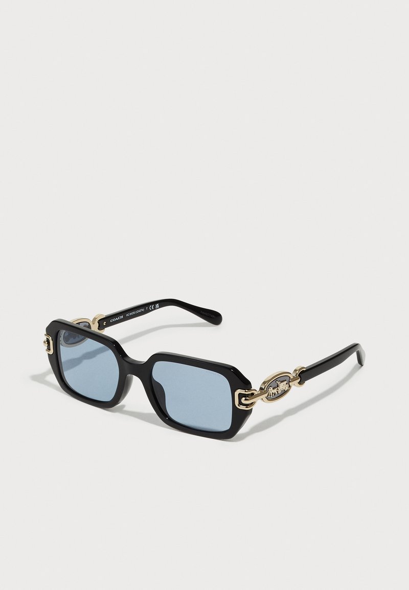Óculos de sol quadrados pretos com lentes azuis. Apresenta detalhes em hardware dourado nas hastes com logótipo. Textura suave, design arrojado.