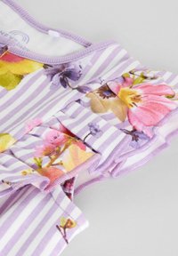 Tissu à rayures violettes avec des motifs floraux en rose, jaune et violet. Présente des accents froncés et un col rond. Matière en coton douce.