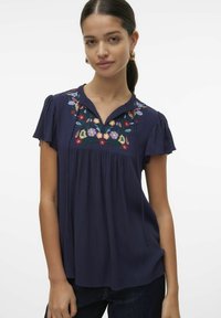 Blusa navy con maniche corte a volant, scollatura a V e ricami floreali colorati sul petto. Tessuto morbido con una vestibilità ampia.