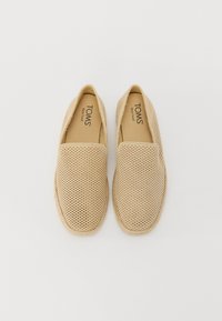 Scarpe slip-on beige con tomaia in tessuto perforato, suola intermedia in juta intrecciata e morbida fodera interna. Con marchio "TOMS" sulla soletta.