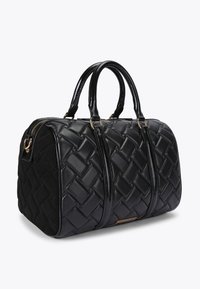 Borsa nera con design trapuntato, texture liscia e doppi manici. Gli accessori in oro esaltano la forma strutturata. Chiusura con zip.