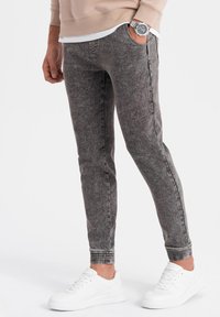 Grå denim joggers med slim fit, elastiska muddar, sidofickor och en texturerad finish, ihop med vita sneakers.