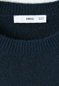 Pulover tricotat de culoare albastru închis, cu guler rotund cu dungi și o etichetă albă care arată mărimea S pentru EUR, SUA și MEX.