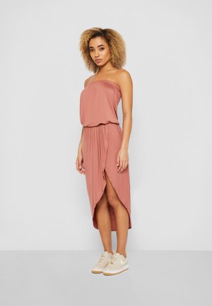 Roze strapless maxi-jurk met een gatherings taille en een split tot boven de dij, gecombineerd met beige sneakers. Zachte, vloeiende stofstructuur.