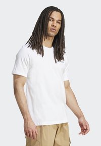 White cotton t-shirt with short sleeves, featuring a small black logo on the chest and a classic crew neckline. Smooth texture.