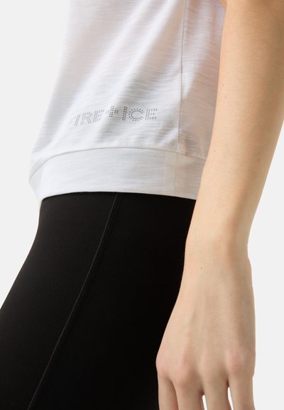 Witte T-shirt met korte mouwen en een gebogen zoom, voorzien van een glanzend "AIR FORCE" ontwerp in stippenpatroon. Gepaarde met aansluitende zwarte leggings.