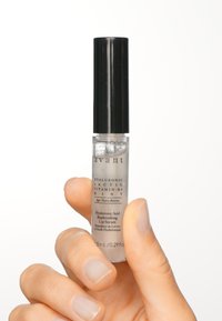 Genomskinlig glasflaska för läppserum med ett svart skruvkork. Texten på etiketten inkluderar "Hyaluronsyra Återfyllande Läppserum." 15 mL storlek.