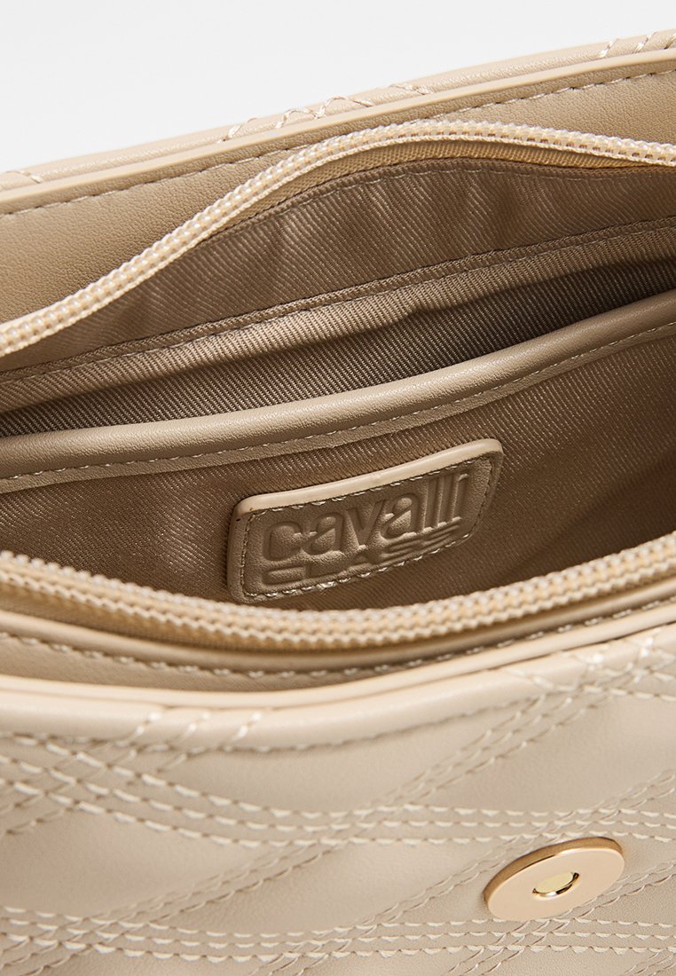 Beiges Handtascheninnere, gestepptes synthetisches Material, mit glatter Textur, goldfarbener Hardware und einem Markenetikett im Inneren.