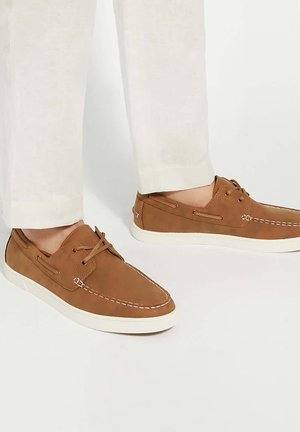 Brown leather boat shoes with white stitching and a white rubber sole, featuring laces and side panels for added detail.