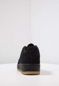 Sneaker nera in suede con suola in gomma, marchio Nike sul tallone e sulla linguetta, colletto imbottito e cuciture dettagliate lungo le cuciture.