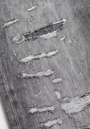 Close-up of gray denim fabric with multiple horizontal rips revealing white threads underneath.