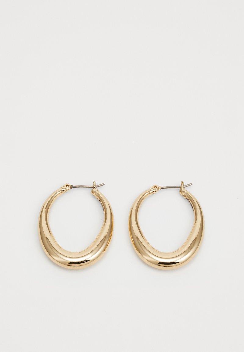 Et par skinnende gullfargede halvmåneformede hoop-øreringer med tynne metalspenner på en hvit bakgrunn.