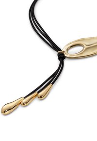 Collier en cuir noir avec trois gouttes d'accent en or et un fermoir basculant en or. Texture lisse et forme ovale allongée du pendentif.