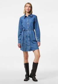 Rochie din denim cu guler, închidere cu butoni și centură din material. Mâneci lungi, culoare albastru deschis și siluetă dreaptă.