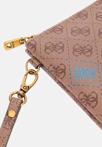 Rudos spalvos modeliuotas rankinukas su auksiniu užtrauktuku, Guess prekės ženklo užtrauktuko traukikliu ir auksiniu užsegimu, pritvirtinančiu dirželį prie krepšio kampo.