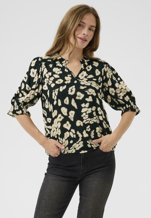 Blouse noire avec un motif floral crème, décolleté en V et manches courtes bouffantes. Tissu doux et coupe décontractée, associée à un jean foncé.