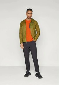 Ελαφρύ μπεζ μπουφάν με καπιτονέ, με κουκούλα, πορτοκαλί πλεχτή ζακέτα, μαύρα παντελόνια και μαύρα αθλητικά παπούτσια. Απλός σχεδιασμός και λειτουργική εφαρμογή.