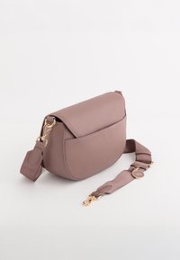 Svetle růžová texturová crossbody taška s zakřiveným tvarem, zlatými kovovými detaily a nastavitelným popruhem. Obsahuje přední kapsu.