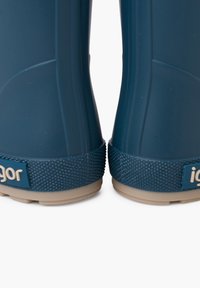 Botas de goma azules con suela de agarre texturizada y acentos beige. Presentan un diseño superior liso y el logo "igor" cerca del talón.
