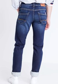 Mörkblå denimjeans med rak passform, med bakfickor med dekorativ sömnad och uppvikta fållar. Läderlappar vid midjan.