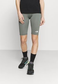 Szare spodenki sportowe o dopasowanym kroju, z logo na dolnym brzegu. W połączeniu z czarnymi butami i skarpetkami, prezentują sportowy wygląd.