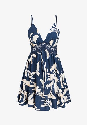 Robe bleu marine sans manches avec imprimé floral blanc, encolure en V profonde, détail en dentelle à la taille et ourlet à volants.
