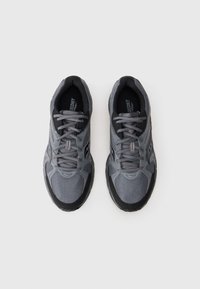 Pár sivých a čiernych bežeckých topánok Saucony s šnúrkami, zobrazené zhora na jednoduchom bielom pozadí.