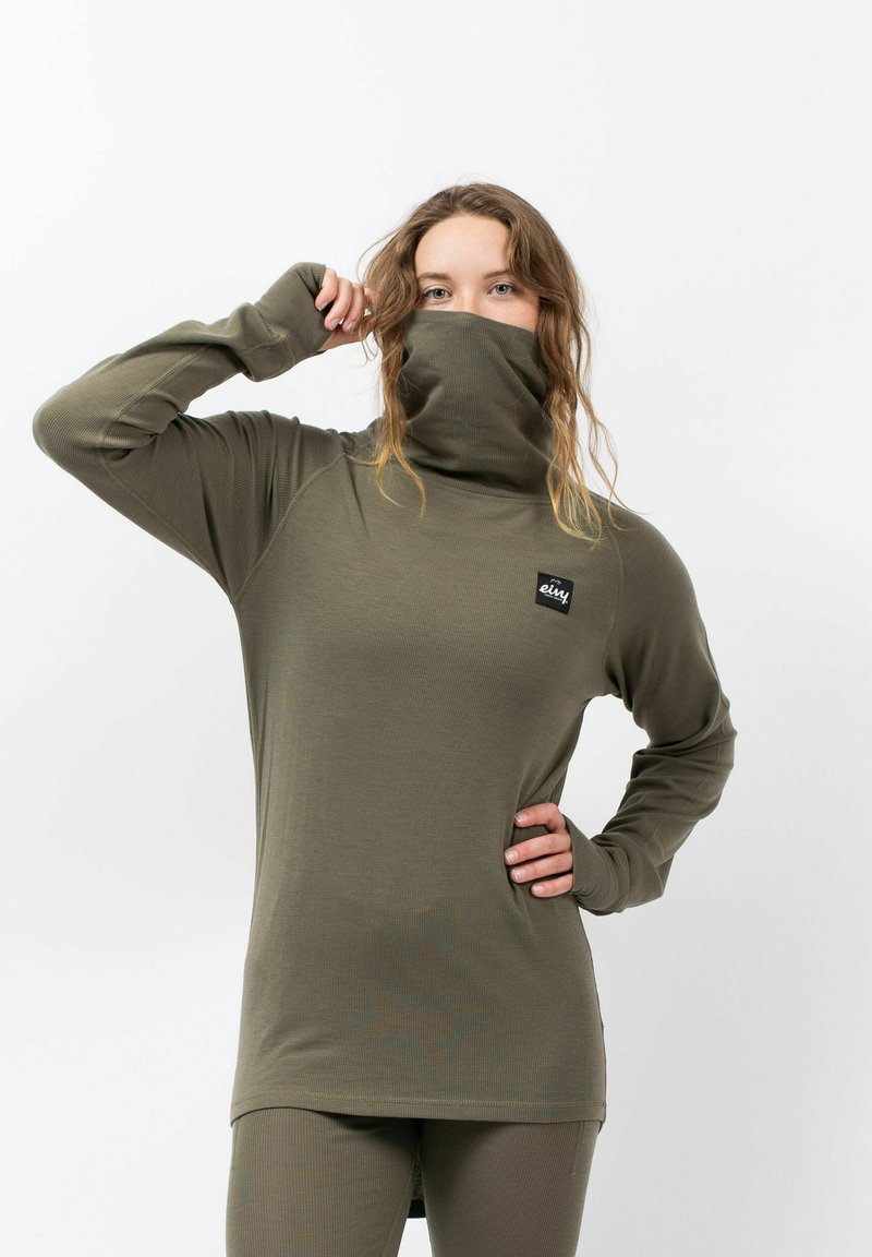 Langärmliges, olivgrünes Oberteil mit hohem Kragen und gerippter Textur; verfügt über ein Logo-Patch auf der Brust. Enganliegendes Design mit Daumenlöchern.