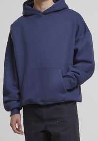 Sweat à capuche bleu marine en tissu doux, doté d'une poche avant et de poignets côtelés, avec une coupe décontractée et des détails de couture minimalistes.