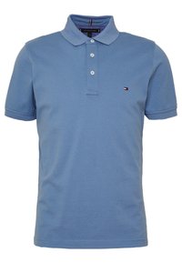 Light blue short-sleeve polo shirt made of cotton. Features a three-button placket and a small brand logo on the left chest.