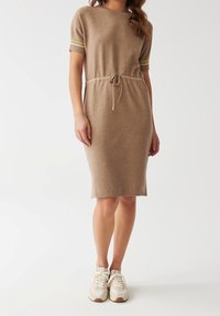 Robe tricotée en marron clair avec des manches courtes, taille à cordon de serrage et accents jaunes sur les poignets. Texture douce, coupe droite, longueur genou.