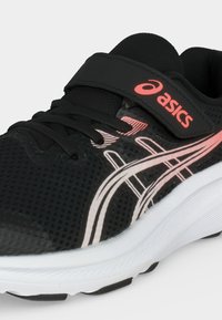 Αθλητικό παπούτσι Asics σε ασπρόμαυρο με ροζ λογότυπο, πλέγμα επάνω μέρος, ιμάντα βέλκρο και κορδόνια σε λευκό φόντο.