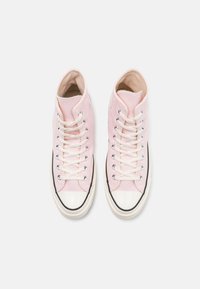 Rosa høyhælte kanvas sneakers med hvite snørebånd, gummitåhette og svart trim. Glatt tekstur med lufthull for ventilasjon.