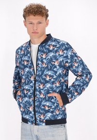Giacca bomber floreale in marine con dettagli in azzurro chiaro e pesca. Presenta una chiusura con zip, polsini a costine e due tasche laterali. Tessuto leggero.