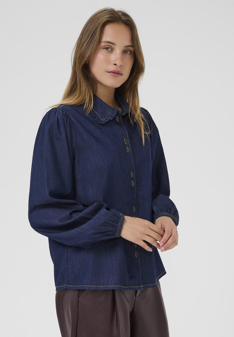 Denim shirt in dark blue featuring a classic button-down design, gathered shoulder details, and long sleeves with elastic cuffs.
