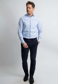 Lichtblauw gestreept overhemd met knopen, donkerblauwe broek, zwarte riem en zwarte laarzen, met een aansluitend ontwerp en lange mouwen.