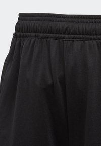 Los pantalones deportivos negros cuentan con una cinturilla elástica, una textura suave y un ajuste holgado, enfatizando la comodidad y la movilidad en el diseño.