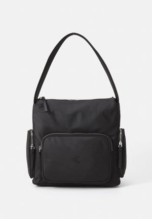 Schwarze Schultertasche mit verstellbarem Riemen, vorderen und seitlichen Reißverschlussfächern sowie einem dezenten, geprägt CK-Logo auf der Vorderseite.