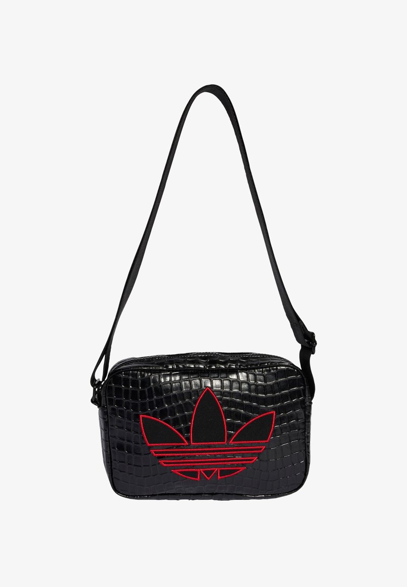 Czarna torba z tłoczonym wzorem krokodyla, z czerwonym wyszywanym logo, o prostokątnym kształcie, z regulowanym paskiem i zamkiem błyskawicznym. Teksturowane, gładkie wykończenie.