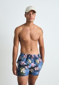 Shorts de baie florale cu bază albastră și modele tropicale în nuanțe de roz, alb și verde. Talie elastică cu detaliu de șnur. Căciulă bej.