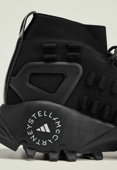 Scarpa atletica nera con tomaia testurizzata, supporto per il tallone in plastica stampata e suola in gomma a motivo con dettaglio del logo.