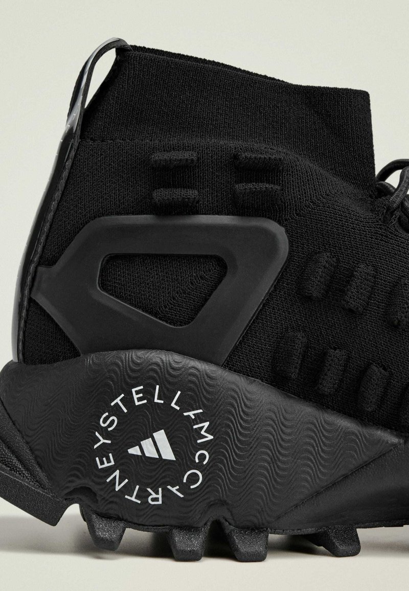 Schwarzer Sportschuh mit strukturiertem Obermaterial, geformter Kunststoff-Fersenschutz und einem profilierten Gummisohle mit Logodetails.