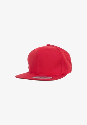 Red snapback cap with a flat brim, structured crown, and smooth fabric texture. Features a circular sticker on the brim.