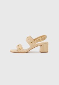 Beige heeled sandals with textured fabric, wide toe straps, gold floral accents, and ankle strap with buckle. Block heel design.
