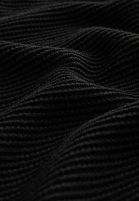 Tejido negro acanalado con textura ondulada y pliegues suaves que crean sombras y luces en su superficie.