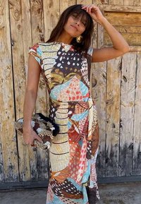Colorful, patterned dress with a fitted top and loose skirt. Features shades of brown, blue, and coral. Clutch purse has bead accents.