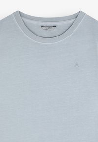 Lyseblå t-shirt med rund hals lavet af blødt bomuld. Har et lille kranielogo broderet i en lysere skygge på venstre bryst.
