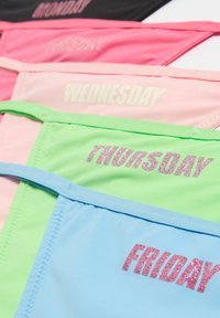 Multikleurige slipjes in zwart, roze, groen en blauw met de dagen van de week gedrukt in glinsterende letters op elke paar.